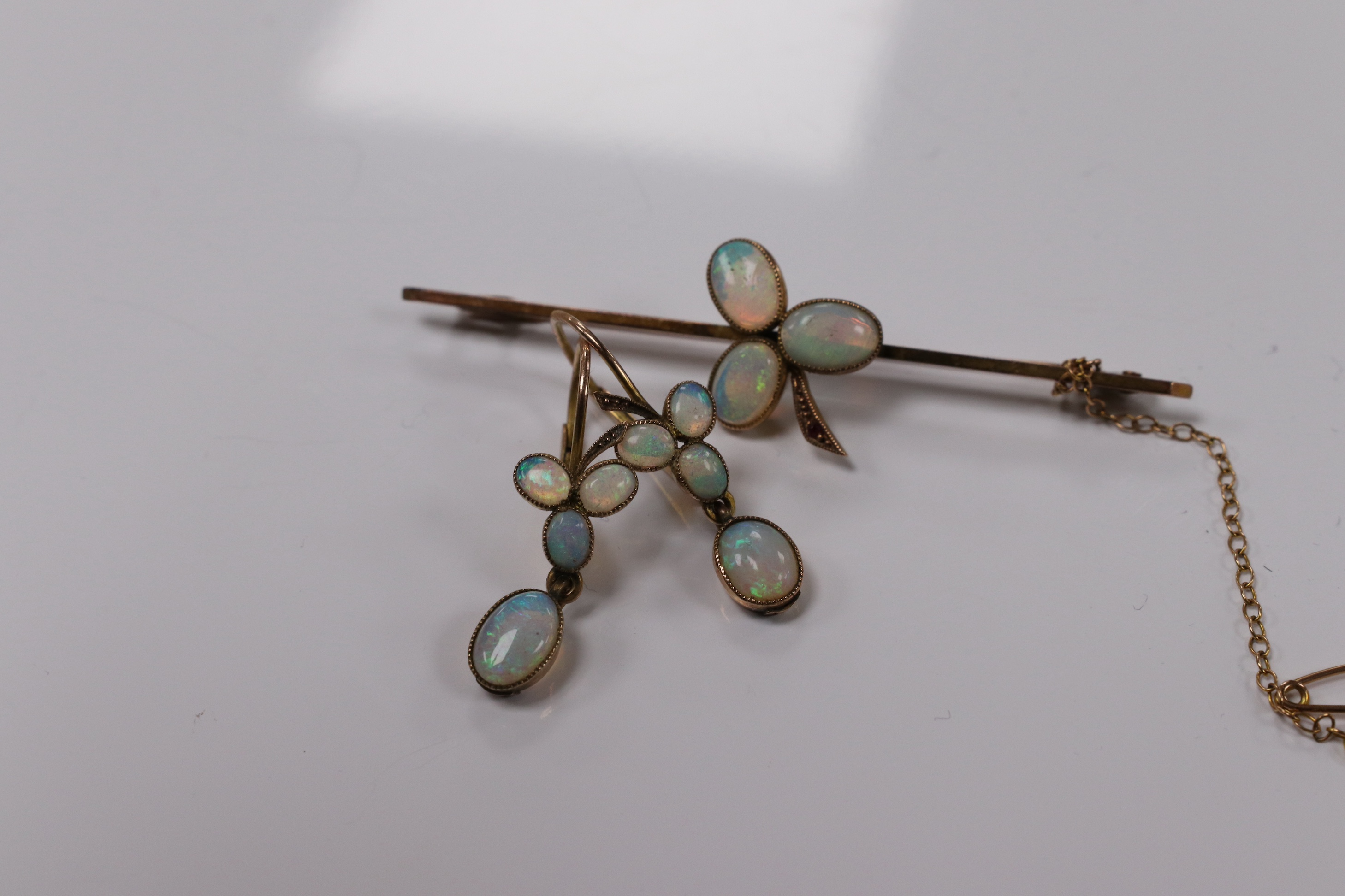 A 9ct and three stone white opal and single stone ruby set bar brooch, 58mm, together with a pair of yellow metal and opal cluster set earrings. Condition - fair